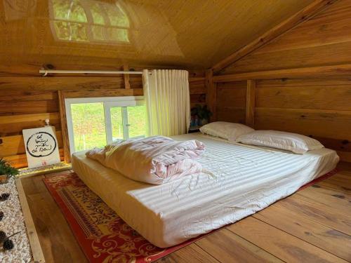 a large bed in a wooden room with a window at BTR Farm in Da Ðeum (2)
