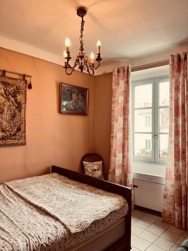 a bedroom with a bed and a chandelier and a window at La Clé de la Porte Rentals in Antibes