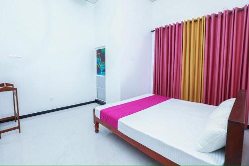 a bedroom with a bed and a colorful curtain at Yala Lemon View in Tissamaharama