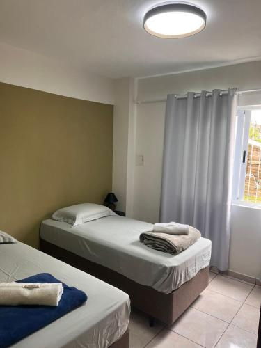 a bedroom with two beds and a window with a light at Apartamento Brisa in Veranópolis