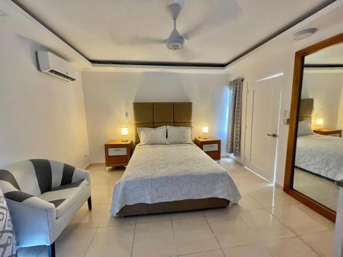 a bedroom with a bed and a chair and a mirror at Villas Carela, Villas Privadas con Piscina y Jacuzzi a 2 Minutos de la Playa de Cabarete in Cabarete