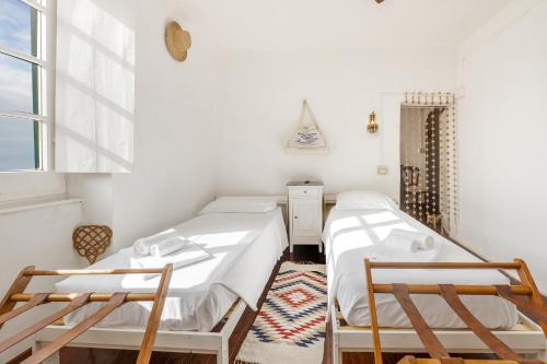 two beds in a room with two chairs and a window at Casa Anita - Storia & Mare in Zoagli