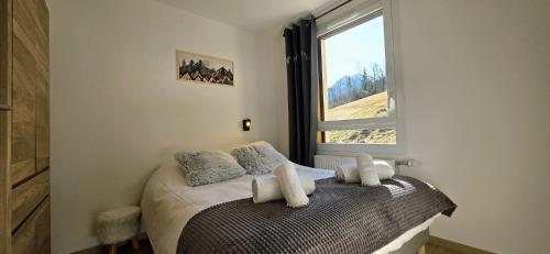 a bedroom with a bed with pillows and a window at Les Chalets d'Offaz - Centre Abondance - Alp'in C in Abondance