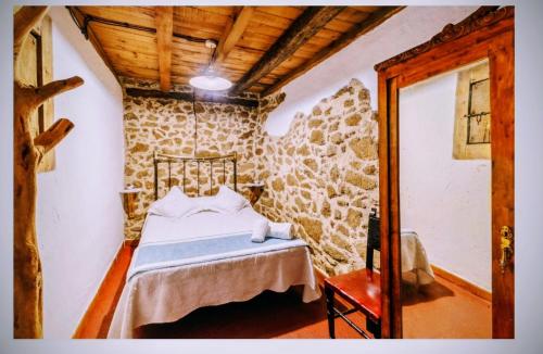 a bedroom with a bed in a stone wall at Tu Casa de Pueblo in La Iglesuela