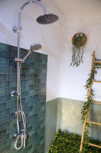 a shower in a bathroom with a blue brick wall at Le Mazet d'Aurore in Chassiers