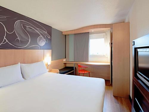 ibis Soissons في سواسون: غرفة فندق بها سرير أبيض كبير ونافذة