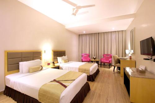 ein Hotelzimmer mit zwei Betten und einem Schreibtisch in der Unterkunft Best Western Ashoka in Hyderabad