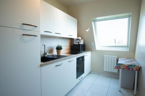 a kitchen with white cabinets and a sink and a window at Le Cocon I Hyper Centre & Calme in Crozon