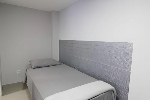 a bed in a white room with a wall at Studio VI - Com Ar Condicionado in Jundiaí