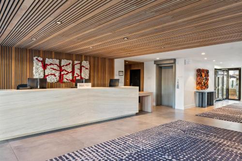 an office lobby with a reception desk and wooden ceilings at The Anthem Los Angeles Stadium District, Tapestry by Hilton in Inglewood