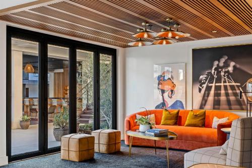 a living room with an orange couch and a table at The Anthem Los Angeles Stadium District, Tapestry by Hilton in Inglewood