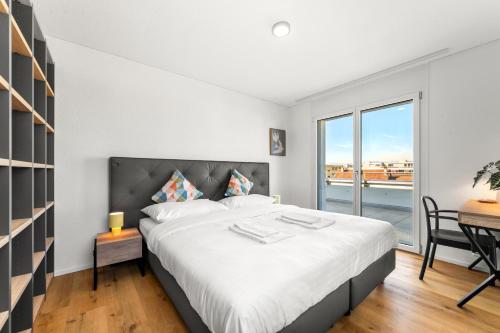 a bedroom with a bed and a desk and a window at Penthouse Exclusif - Grande Terrasse - Avenches - Self Check-in in Avenches