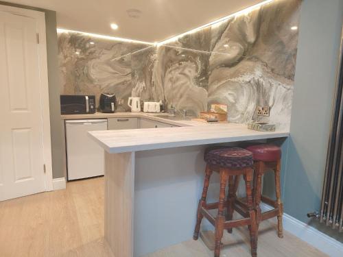 a kitchen with a counter with two bar stools at Tramway Apartment in Blessington