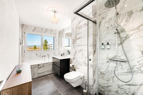 a white bathroom with a shower and a toilet at Penthouse Exclusif - Grande Terrasse - Avenches - Self Check-in in Avenches