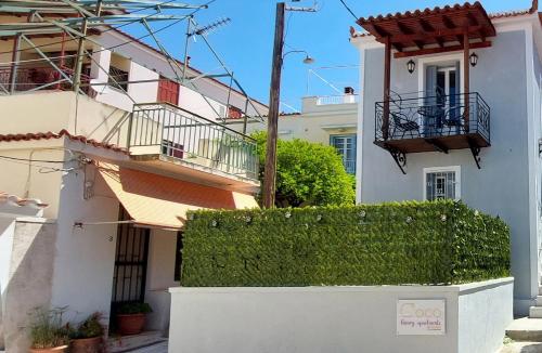 a white house with a hedge in front of it at Coco Luxury Apartments in Poros