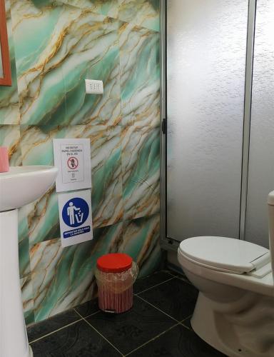 a bathroom with a toilet and a sign on the wall at Cabañas Montina Hualqui piscina y tinaja in Concepción