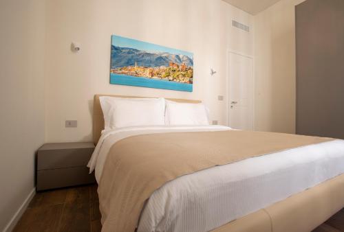 a bedroom with a large white bed with a painting on the wall at Le Due Piazze in Genoa