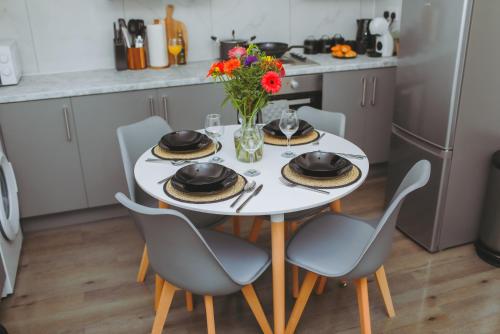 a white table with chairs and a vase of flowers at Perfectly Located City Centre Apartments in Reading