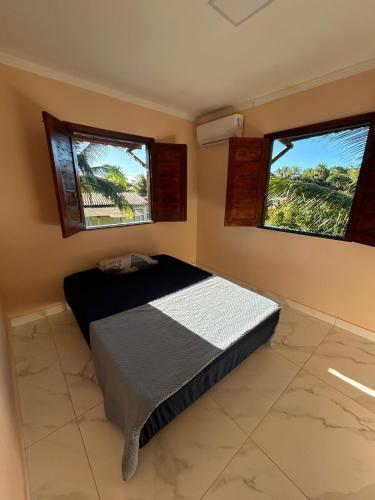 a bedroom with a bed and two windows at Refúgio do Mar in Ilhéus