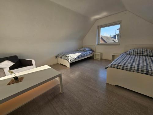 a room with two beds and a table and a window at Gepflegte Monteurswohnung in Rommerskirchen in Rommerskirchen