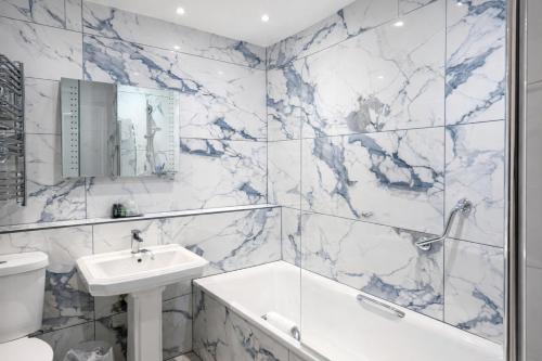 a bathroom with marble walls and a sink and a tub at Friars Carse Country House Hotel in Dumfries