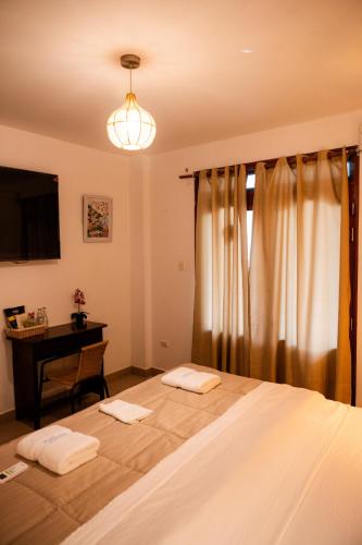 a bedroom with a bed with a desk and a television at Hotel Luna Nueva in Colán
