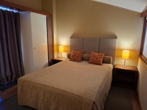 a bedroom with a large bed with two lamps at Clube Pinhal da Foz in Esposende