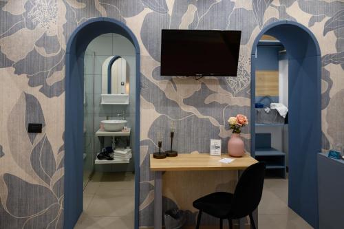 a bathroom with a desk and a tv on a wall at Incanto B&B Cefalù in Cefalù
