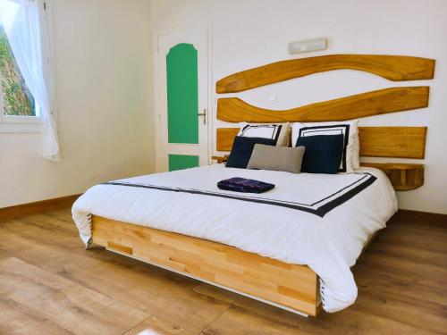 a bedroom with a large bed with a wooden headboard at Domaine La Salamandre - Piscine & Forêt privée, Vue sur Vallée in Lauzerte