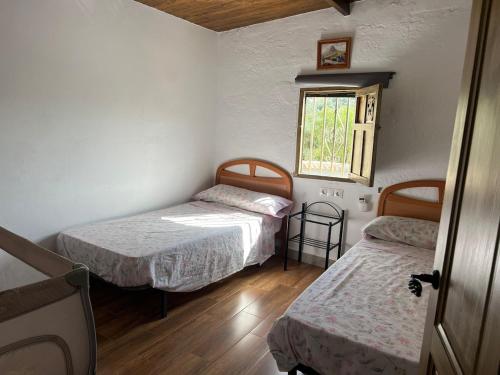 two beds in a small room with a window at Cortijo rural Los Pinos in Villanueva de Algaidas