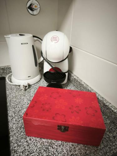 a red box sitting on a counter next to a coffee maker at Art House Madeira II in Caniço