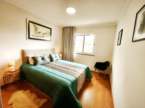 a bedroom with a bed with a green blanket at Art House Madeira II in Caniço