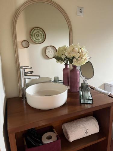 łazienka z umywalką, lustrem i kwiatami w obiekcie Roça Vale dos Prazeres w mieście São Tomé