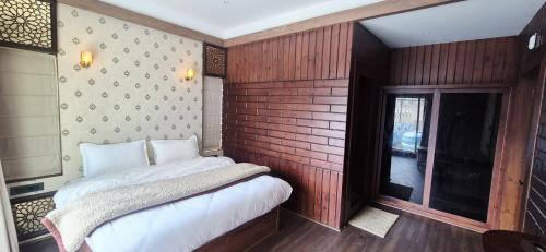 a bedroom with a bed and a brick wall at Pine Breeze Luxe in Gulmarg
