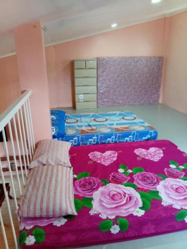 a bedroom with two beds with pink roses on a rug at cavinitan transient house in Virac