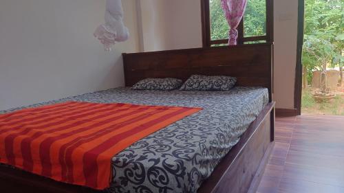 a bedroom with a bed with a wooden headboard at ELEPHANT Orphanage View in Udawalawe