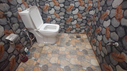 a bathroom with a toilet and a stone wall at ELEPHANT Orphanage View in Udawalawe