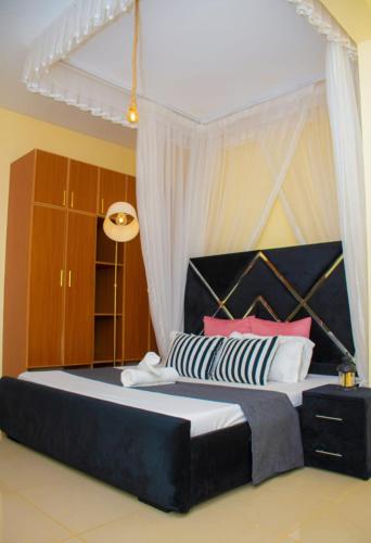 a bedroom with a large bed with a black headboard at Mystic cabins in Nyeri