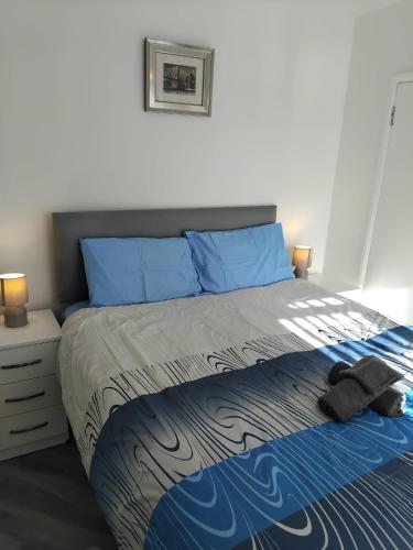 a bedroom with a bed with blue sheets and blue pillows at Robin's Accommodation in Wythenshawe
