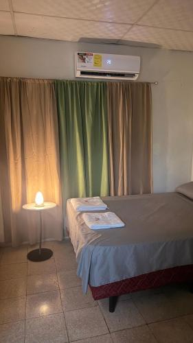 a bedroom with a bed and a table with a lamp at Hostal Flores in David