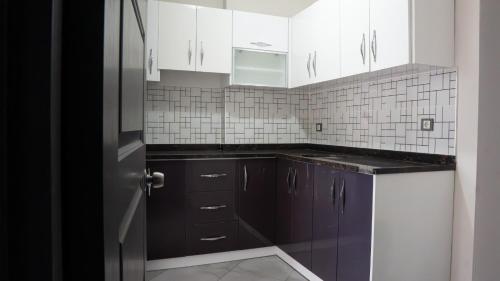 a kitchen with white cabinets and a purple refrigerator at We Nirvana Otel in Mezitli