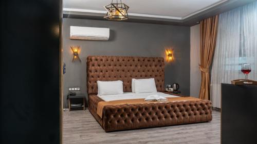 a bedroom with a large bed with a leather headboard at We Nirvana Otel in Mezitli