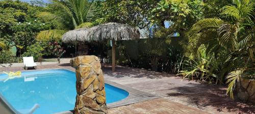 a swimming pool in a garden with a umbrella at Vila Pescador Fortim in Fortim