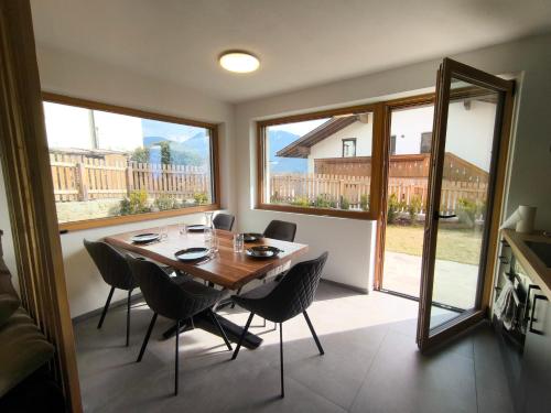 a dining room with a table and chairs and windows at SiLENA Dolomites in Laion
