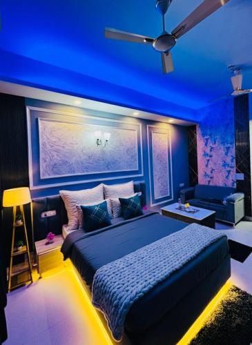 a bedroom with a blue ceiling with a bed and a couch at Mansion Grey Studio in Ghaziabad