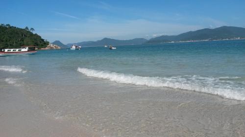a beach with some boats in the water at Loft Florianópolis no Campeche in Florianópolis