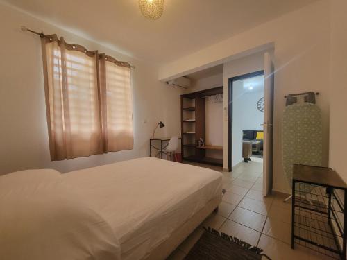 una camera da letto con un letto bianco e un tavolo di Bacaba Appart a Cayenne