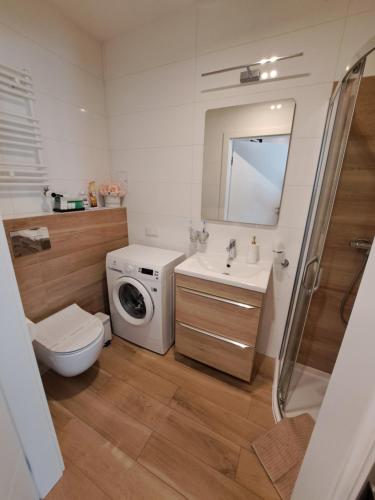 a bathroom with a toilet sink and a washing machine at Apartament RUBUS 305 Sofii in Świnoujście