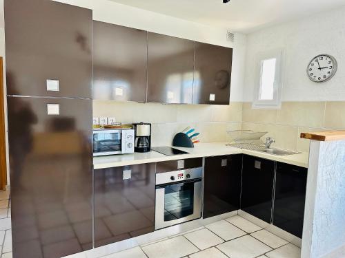 a kitchen with stainless steel appliances and a clock on the wall at "Le Cade" - Résidence Rive Gauche in Les Salles-sur-Verdon