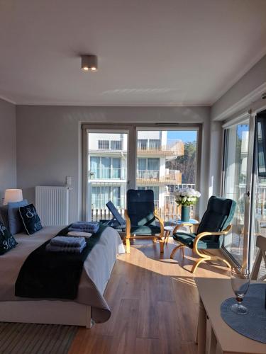 a bedroom with two chairs and a bed and windows at Apartament RUBUS 305 Sofii in Świnoujście